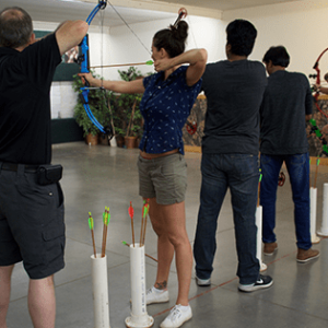 coworkers holding bows and arrows in an archery class together