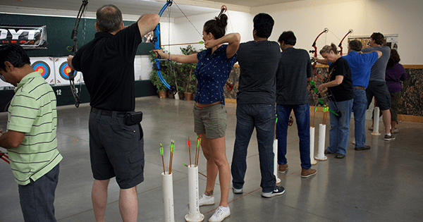 coworkers holding bows and arrows in an archery class together