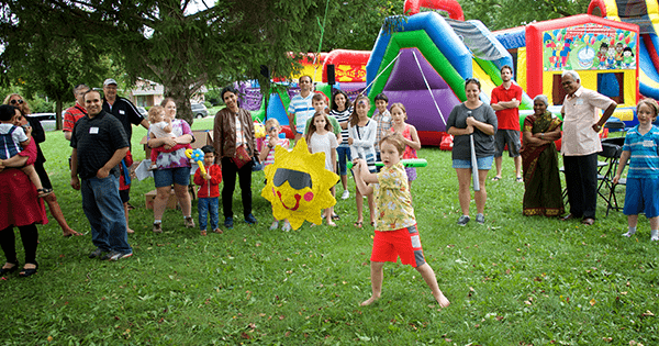 child hitting a sunshine pinata at a summer picnic