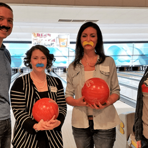 Coworkers bowling with fake mustaches
