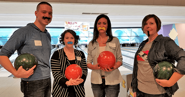 Coworkers bowling with fake mustaches