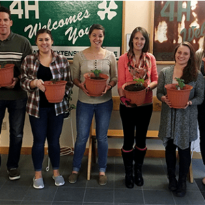 coworkers smiling together holding individual plants