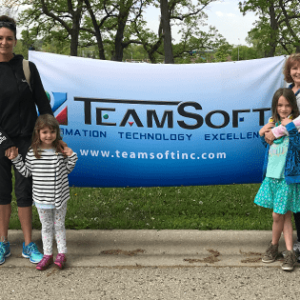 Children and adults standing in front of a TeamSoft banner sign