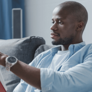 man turning a page while reading a red book
