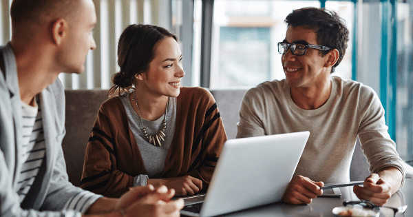 coworkers sitting around a laptop smiling