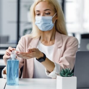 Woman wearing mask applying hand sanitizer