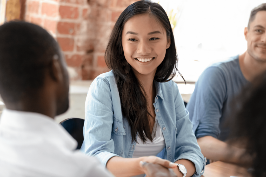 Young coworker smiling and shaking hands with team member