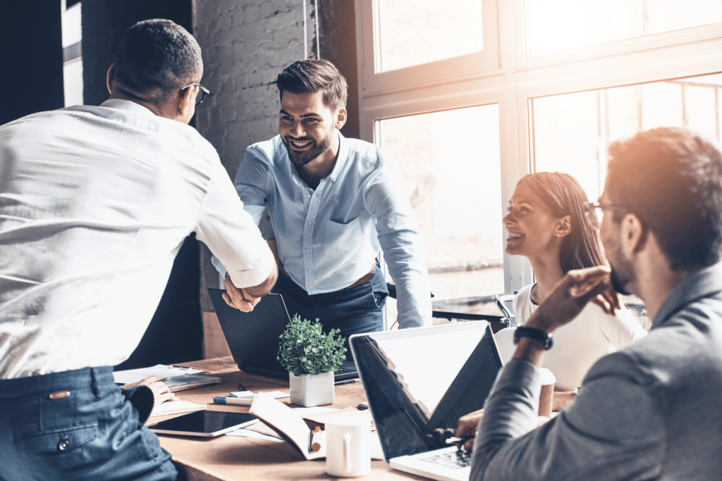 2 men shaking hands in front of coworkers