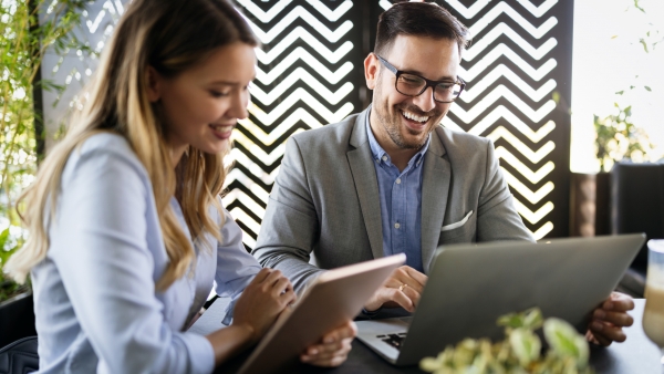 2 coworkers smiling and laughing while on computers