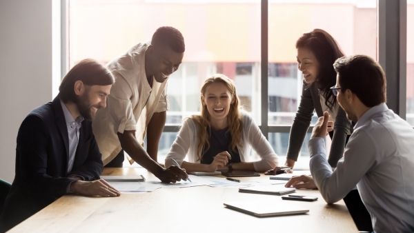 workers gathered around a table meeting and laughing