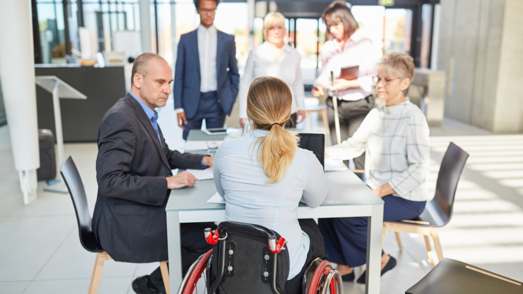 Woman in a wheelchair speaking at a table with coworkers