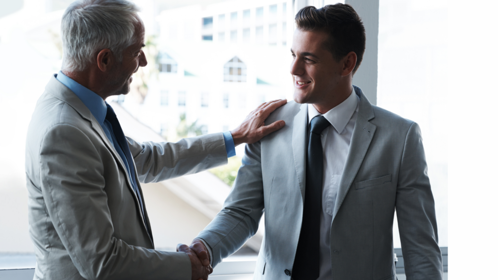 Two men in suits shaking hands and smiling