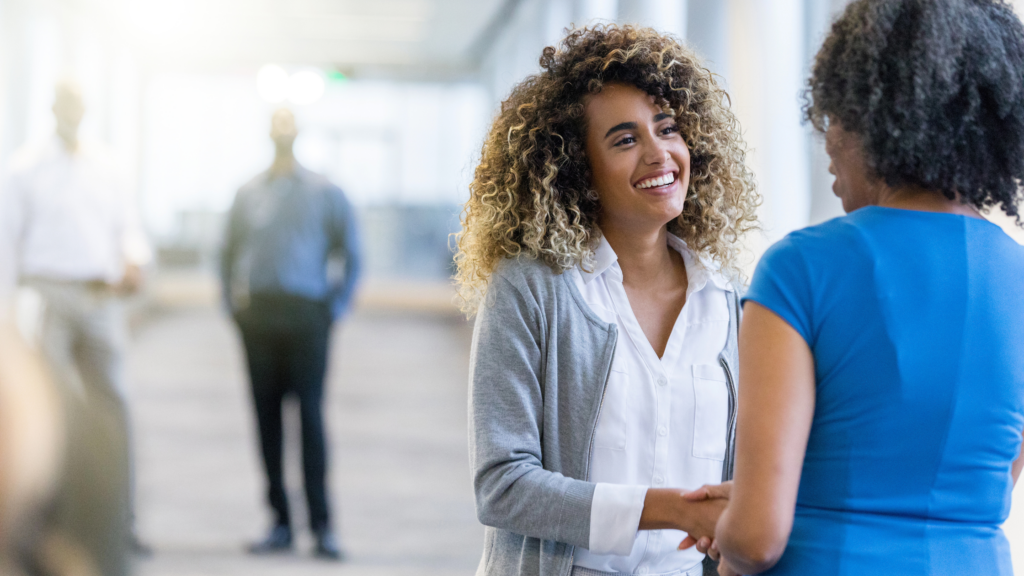 Two women shaking hands and smiling in an office